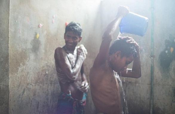 Chlapci se sprchují v továrně, která je zároveň místem, kde kvůli pracovnímu vytížení jedí a spí.  