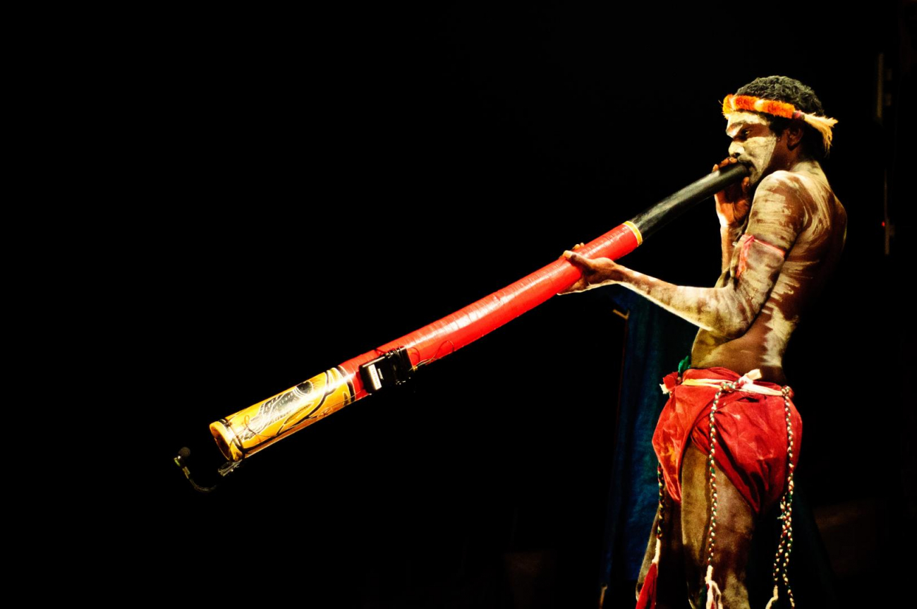 Aboriginec hrající na didgeridoo.