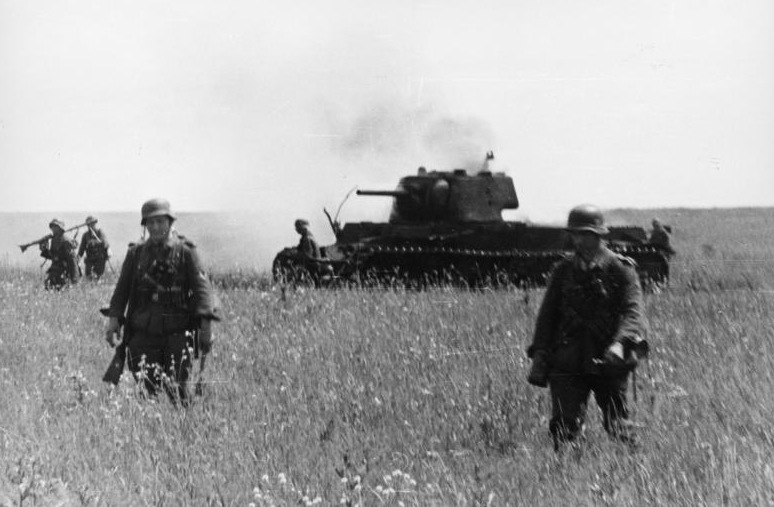 Postup německé pěchoty. Na pozadí zničený sovětský tank