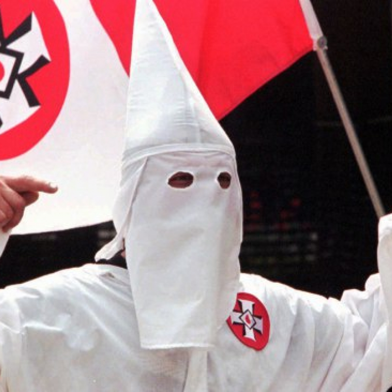 Člen KKK s vlajkou s logem Ku-klux-klanu